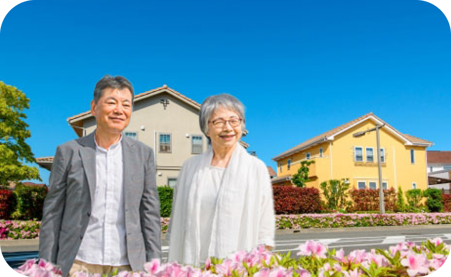 老夫婦が微笑みながら自宅の前で立っている様子